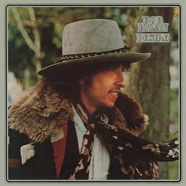 Album Art of Bob Dylan's Desire album - A young man with a short beard and mustache is shown from a profile, mostly hidden under a large grey brimmed hat and a colorful coat with a fur hood. He's looking off to the right and smiling, and there seems to be trees behind him. Around the border of the photo is a black outline and a gray background, and printed in the top right of the photo is the artist's name and the album title in gray with a white, black then gray again border around the text.