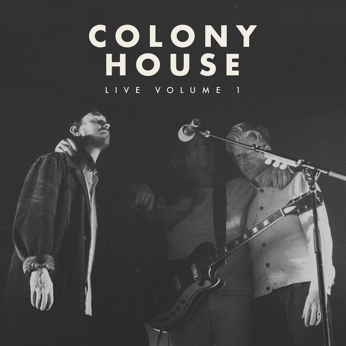 Album Art of Colony House's Live Vol. 1 album - A black-and-white photo of four men huddled together around one microphone in a mostly dark area, definitely very black behind them and mostly lit from the right side. The two men on the outsides are the most visible, and they are both wearing button-down shirts and dark pants. The person close to the microphone is mostly in the dark, but has a guitar hanging around his neck and he's not playing it, he's got his arms around his bandmates.</body></html>