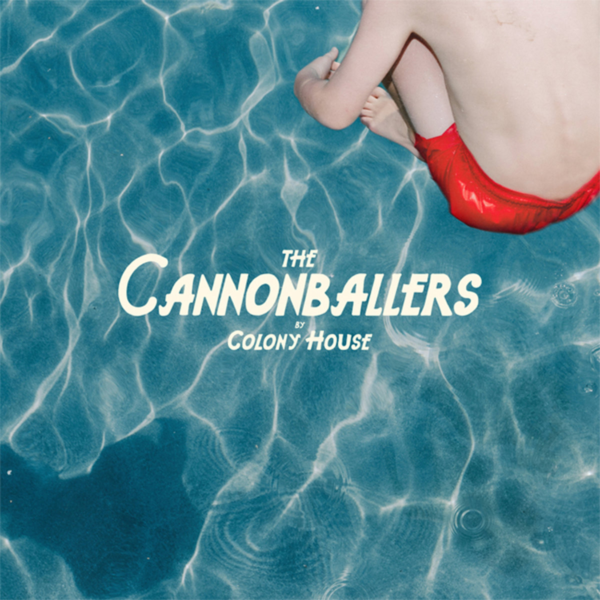 Album Art of Colony House's The Cannonballers album - A photo of a pool from above, with an aqua blue hue and parts of it are whiter than others from the light bending through the water. In the top right, above the water is the torso and arms and legs of a white kid in red swim trunks, with his legs tucked under his chest. In the bottom left, you can see his shadow on the water. In the middle, printed above the photo is 'The Cannonballers by Colony House', in an off-white color and a jaunty font, with the album title bigger and the band name smaller.