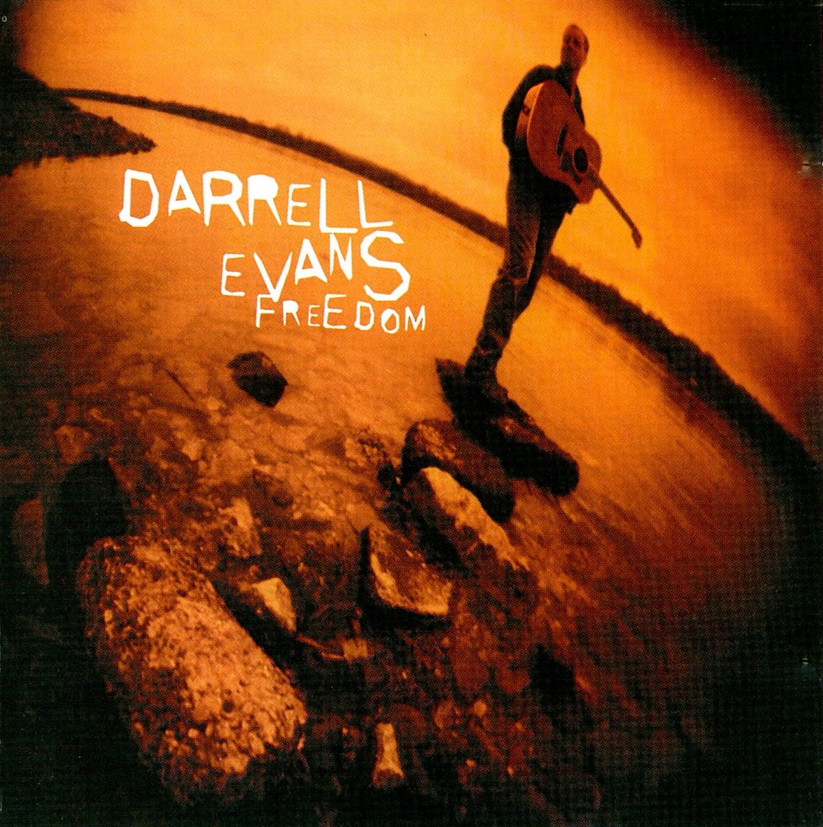 Album Art of Darrell Evans's Freedom album - A very wide-angle lens shows a black-and-white photo where the white is replaced with a gold color. The majority of the photo is of some water and a series of large stones jutting out into the water. A shoreline can be seen on the edges. On the farthest stone out stands a man holding an acoustic guitar, and due to the wide angle, he's somewhat distorted as he's to the top and edge of the frame.</body></html>