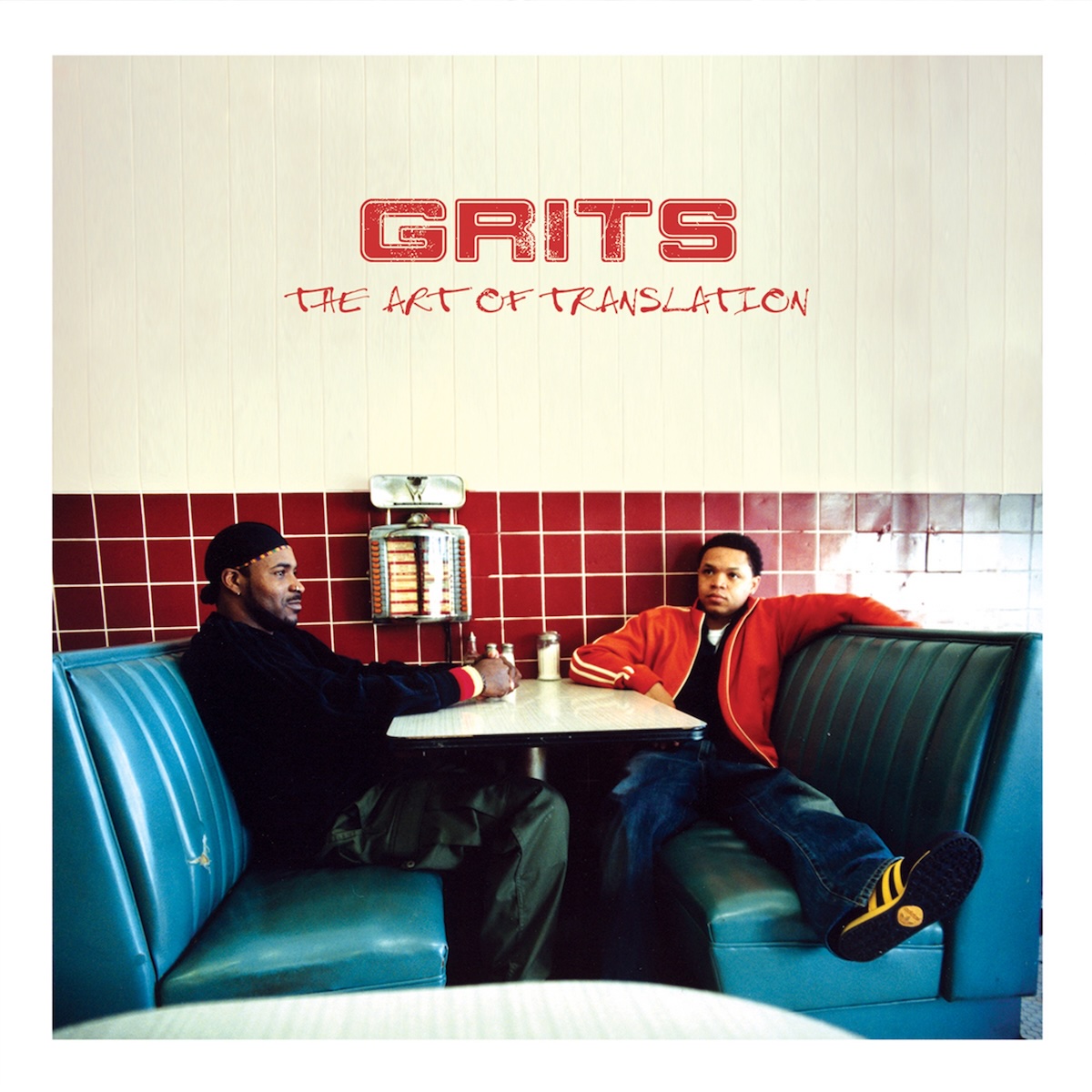 Album Art of GRITS's The Art of Translation album - With a thick white border, a photo of two black men sitting in blue padded benches of what looks like a very standard American diner. The wall behind them is dark red tile, and the table is white. There is a Nickelodeon, a machine to request songs from the jukebox, on the wall next to the table, and a few condiments as well on the table. The two people are sitting on opposite sides of the table and are not looking towards the camera.</body></html>