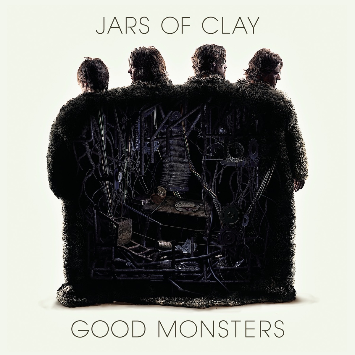 Album Art of Jars Of Clay's Good Monsters album - On a white background with a hint of a creamy green hue, four men are photographed from behind standing together, either wearing black furry suits from head to toe or maybe all with a furry black rug covering their backs. The black back of the furry costume has on top of it a mess of pipes, billows, an overturned chair, and much more. It's probably meant to allude to the complicated internal machinery of humans and/or the band. In the off-white background, above this is printed in large black letters the band's name, and at the bottom the band's name in about the same size as well.