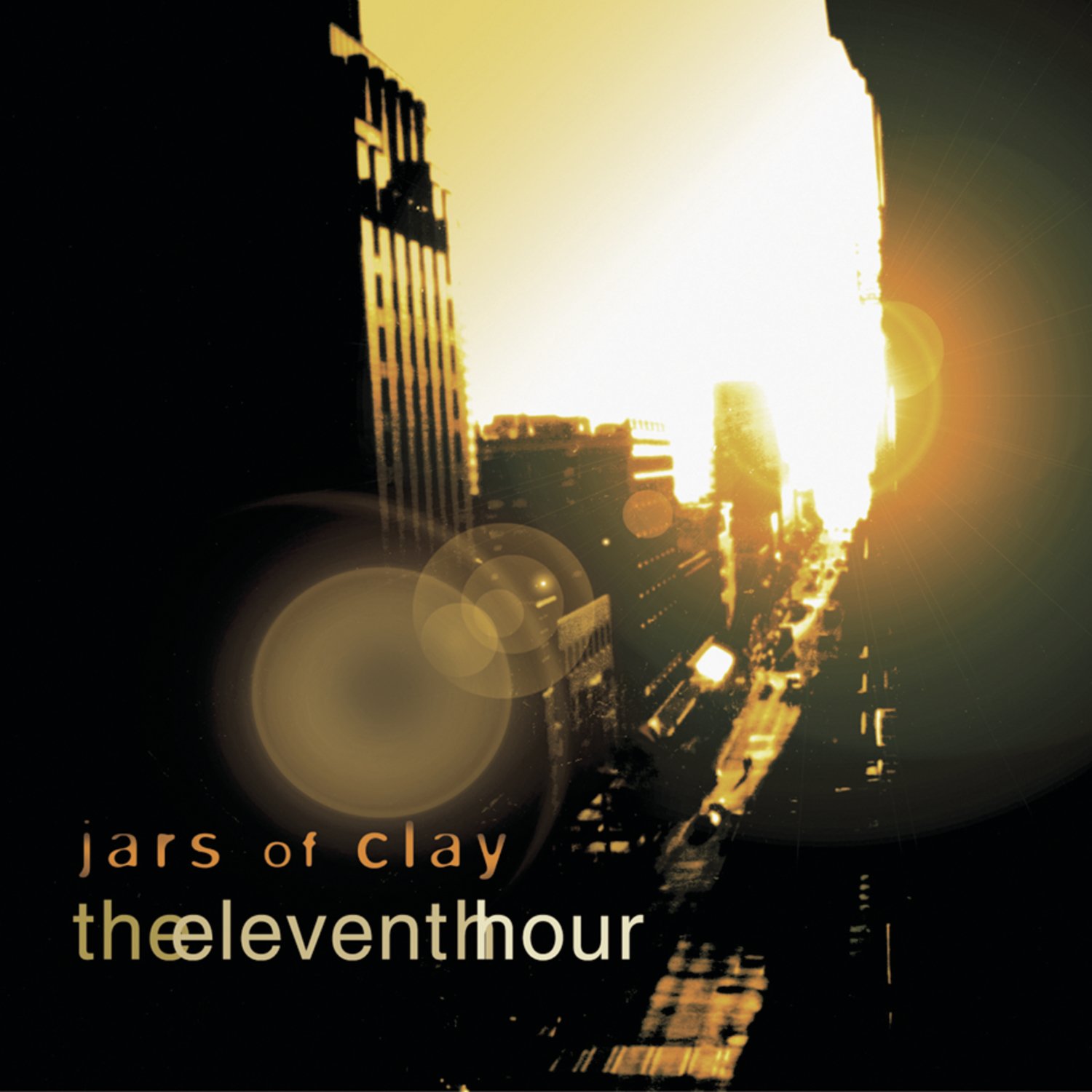 Album Art of Jars of Clay's The Eleventh Hour album - A photo the sun setting down at the end of a long street lined with tall buildings, maybe in a place like New York City. It's taken from high up and far away so it's not too easy to make out details, but cars can be seen on the street, though from how small they are, it's hard to tell what time period the photo was taken in. Both sides of the photo are black, and the buildings make a bit of a cavern for the sun to shine through.</body></html>