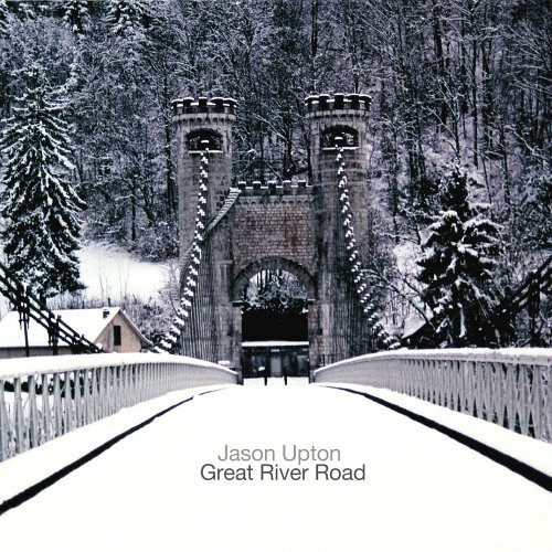 Album Art of Jason Upton's Great River Road album - A nearly black-and-white photo of a winter landscape, mostly snow-covered pine trees in the background. Also what looks like a house can be seen in the background to the left. The center of the photo is a snow-covered bridge going over an unseen river with railings on the sides and a large series of cables holding the bridge up. On the far end of the bridge, in the center of the photo, are large stone towers connected by a stone arch over the roadway. The cables extend from the top of the tower and the cap of the tower and the stone that connects them have stones that go up and down, like a medieval castle. Above the snowy roadway in the photo is printed in gray the artist's name and in black the album title below it.