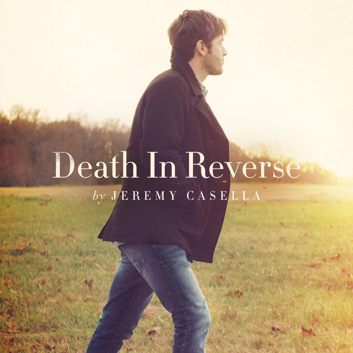 Album Art of Jeremy Casella's Death In Reverse album - A photo of a white man striding across a grassy field with a line of trees off in the distance. The man is striding to the right and is wearing blue jeans and a black coat, and has brown hair. he is looking away from the camera towards the sunset, which seems to be just around the right edge of the frame near the horizon.</body></html>