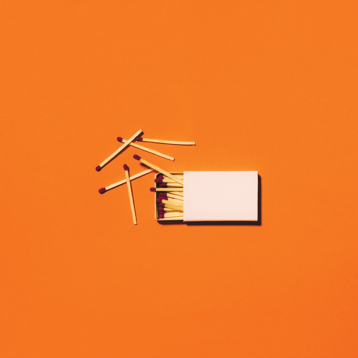 Album Art of Jesus Culture's Living With A Fire album - On a bright orange background, in the middle of the cover there's a white matchbook opened on the left side which is full of matches. Six matches are sitting haphazardly to the left of the matchbook.