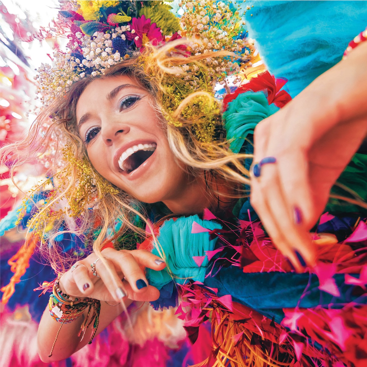 Album Art of Lauren Daigle's self-titled album - A photo of a young woman peering into a camera with a gaping wide smile. Her hands, each nail painted a different color, are near her chest and reaching towards the camera. On her head, mixed in with her brownish-blond hair is a bunch of flowers and feathers, it seems, of all colors.</body></html>