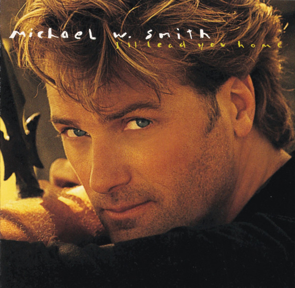 Album Art of Michael W. Smith's I'll Lead You Home album - A photograph of a young, white main with stubble and tousled brown hair looking over his shoulder into the camera, and leaning up against a fence or something. It's a very close-up photo of his face, so not much can be seen of the background or the black shirt he's wearing.</body></html>