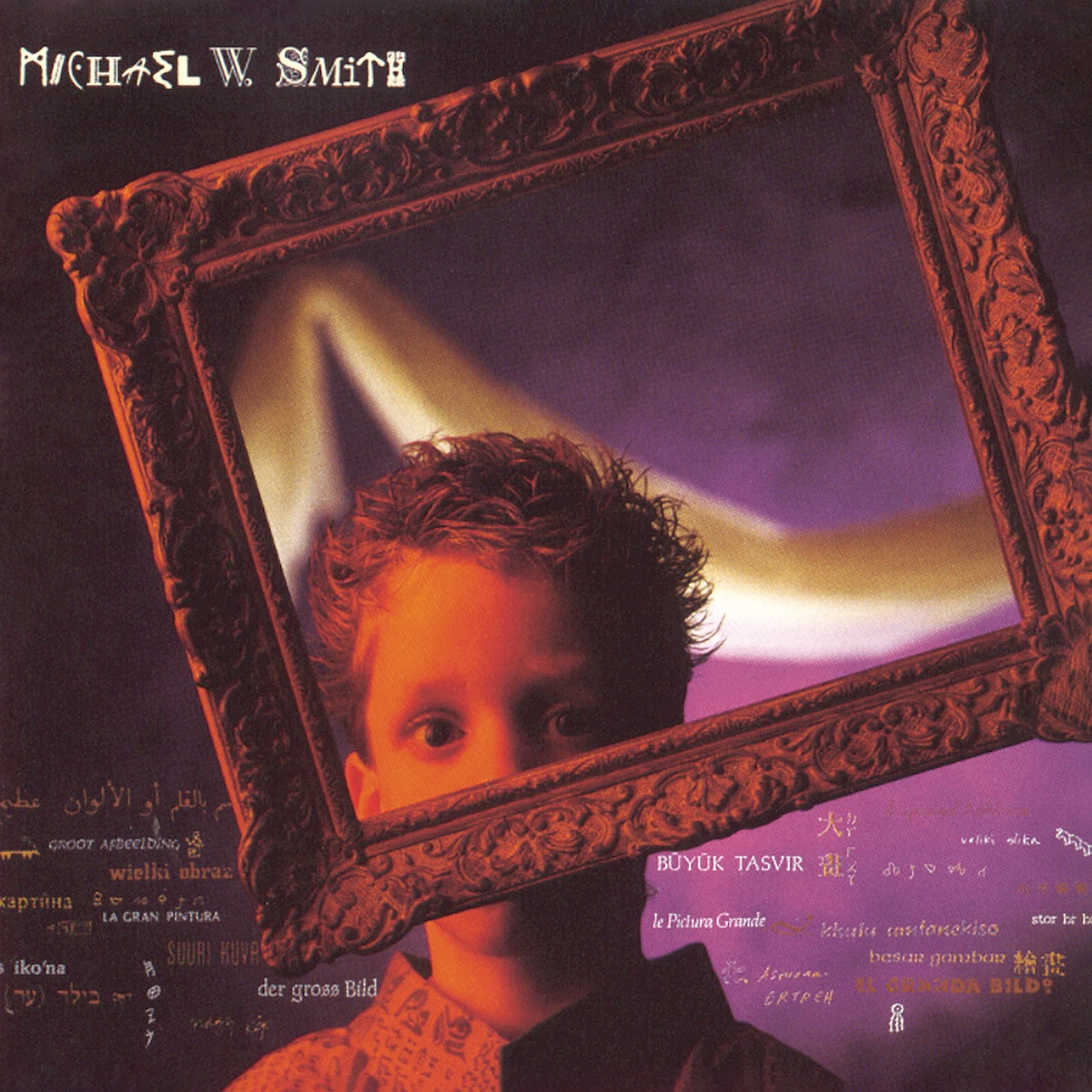 Album Art of Michael W. Smith's The Big Picture album - A photo of a boy of maybe 10 years old from the shoulders up sitting in front of a purple and black background with a golden white cloth hanging in front of the blurry background. The kid is wearing a shirt with words or symbols printed on it and is lit from the left side with an orange light.</body></html>