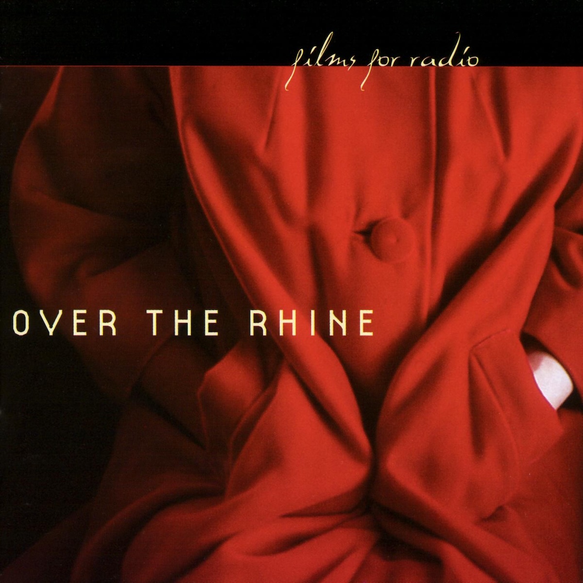 Album Art of Over The Rhine's Films For Radio album - A color photo of a woman wearing a bright red coat with her hands in the pockets takes up most of the space. It looks like she is sitting and her hands are stuffed in the pockets, though we cannot see her shoulders, head or legs. It's mostly just a lot of folds of the coat in light and shadow, with a bit of white skin on the left arm just outside the pocket. On top of the photo is printed in large, light gold text the band's name on the left side. At the top, there's a large horizontal black space above the photo, and printed right above the photo is the album title in a gold, handwriting-style script.