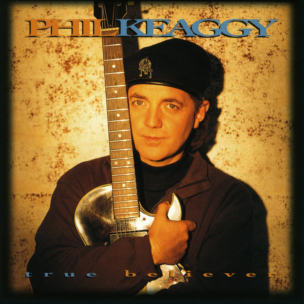 Album Art of Phil Keaggy's True Believer album - A photo of a middle-aged white man holding a shiny, silver guitar in an embrace, his arms around the body of the guitar and the neck up next to and above his head. The man is looking at the camera with a pretty blank expression and is wearing a brown jacket over a black turtleneck and a black beret on his head.</body></html>
