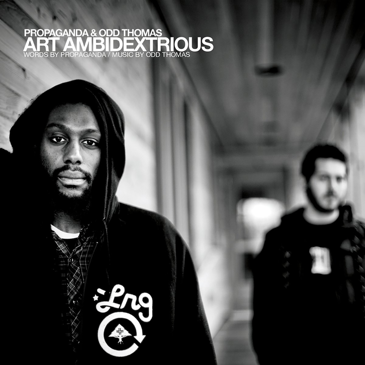 Album Art of Propaganda and Odd Thomas's Art Ambidextrous album - A black-and-white photo of two men in a long hallway. On the left is a black man in a black hoodie with the letters 'Lrg' printed on the front. A dozen feet down the hallway on the right is a white man with a beard and black hair and also in a black hoodie. Like most of the hallway in the background, this man in the background is a bit blurry.</body></html>