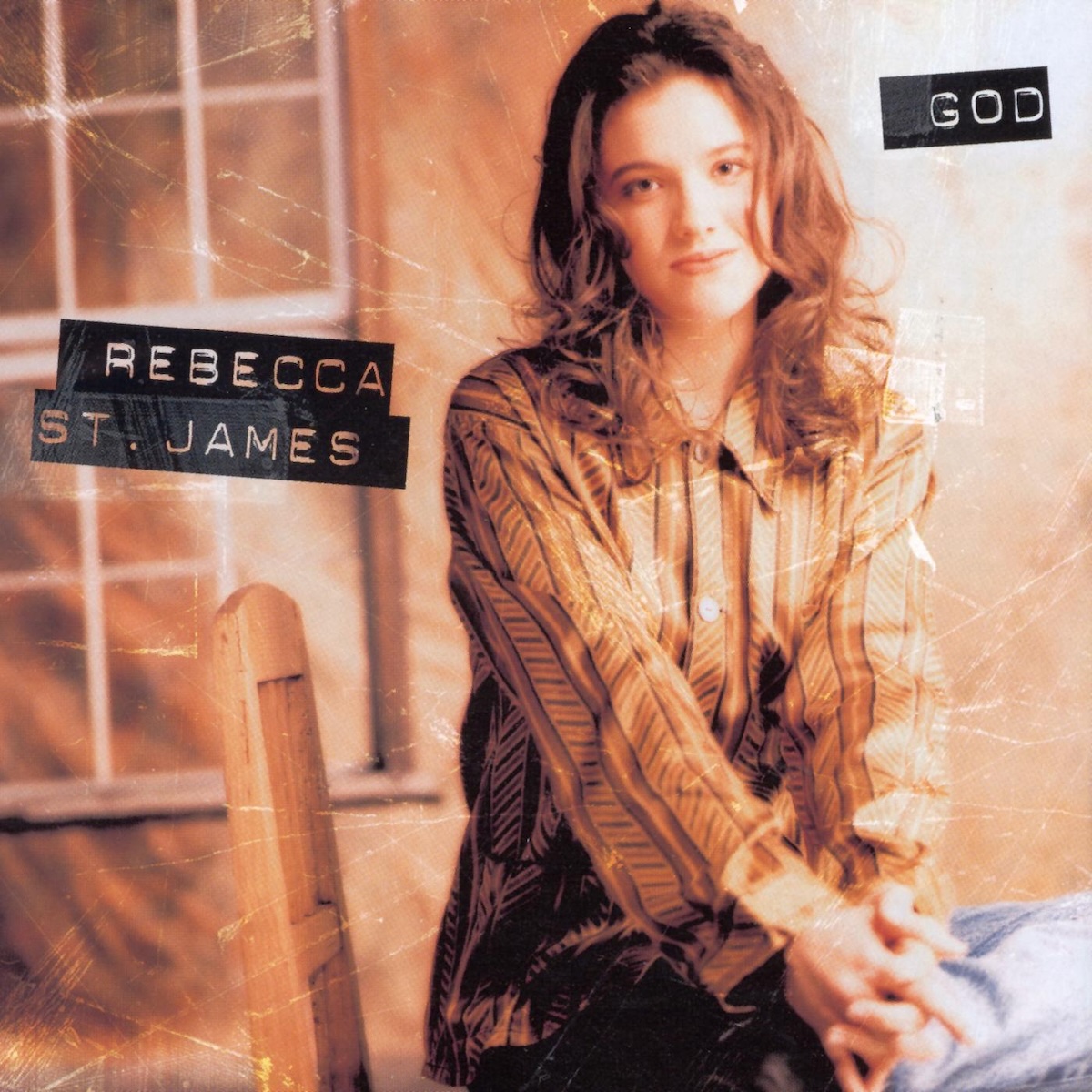 Album Art of Rebecca St. James's God album - A photo of a woman sitting on a chair sideways facing the camera with her left leg sitting on her right. She's wearing an orange, button-down shirt and also sitting in front of an orange background with a window frame design off to the left. She has brown hair that curls past her shoulders and a beautiful face with an almost-smile. Her hands are clasped together out in front of her, resting on her leg. On top of the photo are a bunch of fold/distress marks and some clear tape. On the left side, there's a black label-maker style font that has the artist's name, and on the top right it has the album title in the same font.