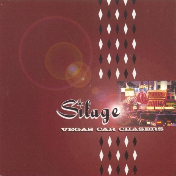 Album Art of Silage's Vegas Car Chasers album - On a dark red background with white and black diamond pattern going down the middle from top to bottom, there's a photo of the Las Vegas strip with cars in the foreground and buildings covered in neon lights in the background on the right side, and to the left of that is the band's name in a style that looks like a retro ad with black text with a white outline and drop shadow, and a star instead of the dot in the 'i'. Below the band name is the title in smaller, simple white text. Right behind the 'e' in the band name is a light source and a lens flare spreads across the background.