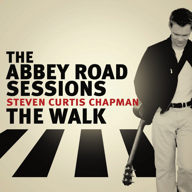 Album Art of Steven Curtis Chapman's The Abbey Road Sessions EP - On a gray background with a bit of a white glow in the middle, a white man is strolling on the right towards the camera, with a guitar slung on his back, towards the camera and looking down. Behind him, in black are the rectangular shapes of a crosswalk. Above that is printed the EP title and 'The Walk' in black in large letters, with between those two the artist name in smaller, red letters.
