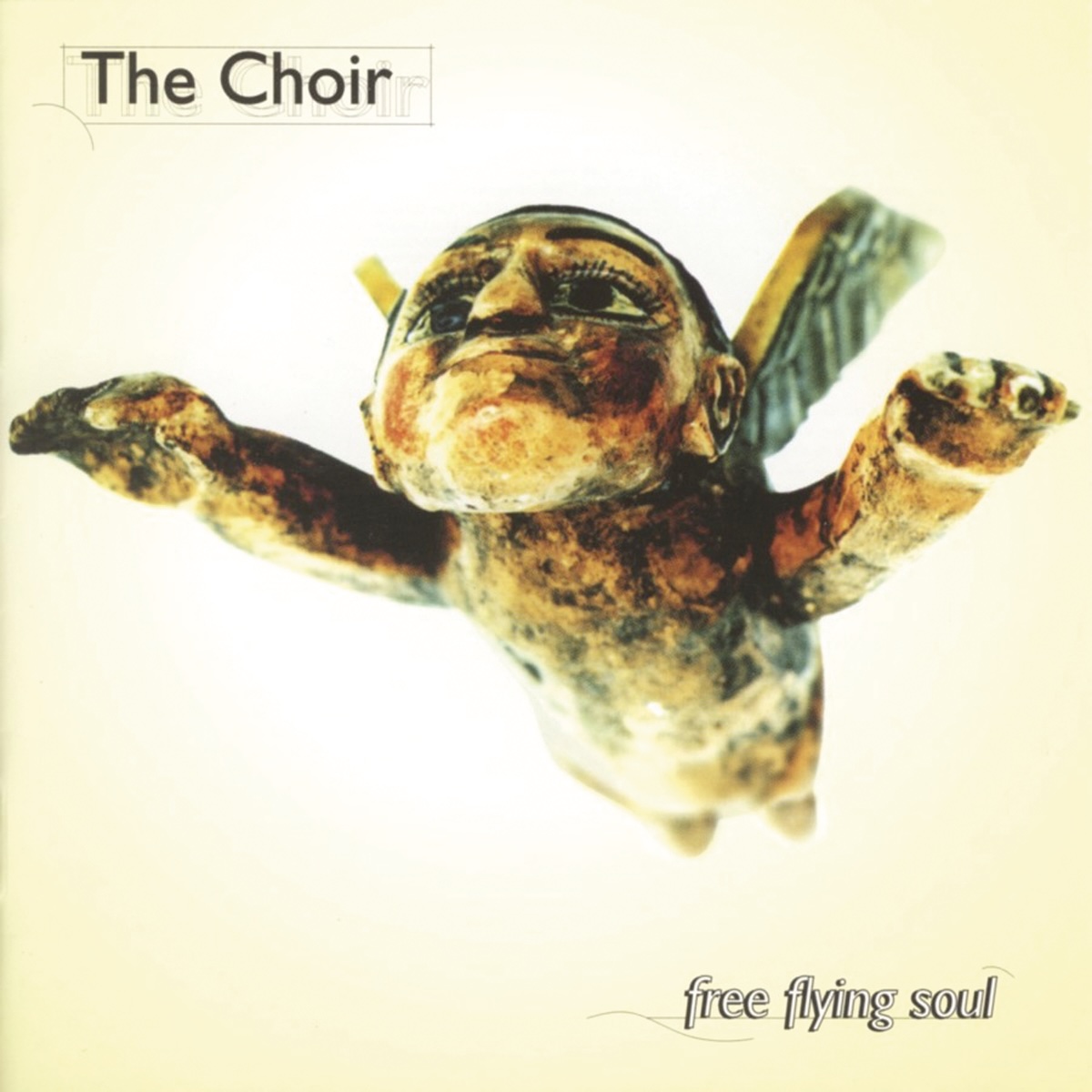Album Art of The Choir's Free Flying Soul album - On a golden yellow background on the edges which fades to white in the center, what looks like some sort of stone or wood carving of a winged man flying towards the camera from above. His hands are stretched out above the camera and he's looking ahead, above the camera. He's got a big chin and large eyes that seem to be painted on. In the top left, the band name is printed in a hairline box, and in the bottom right, the album title is printed in smaller text on a hairline baseline.