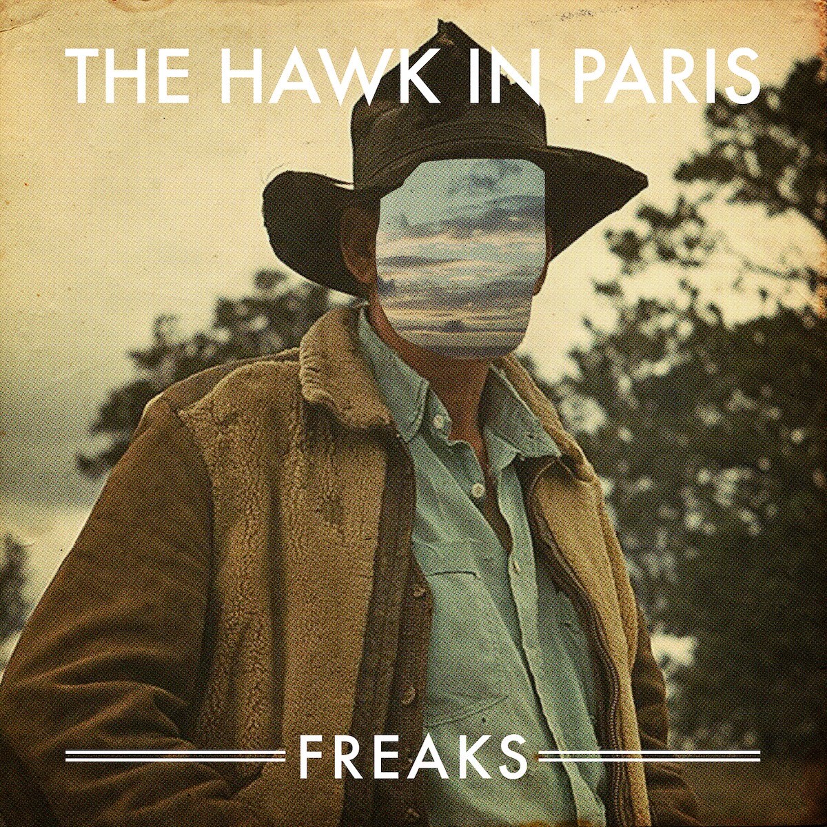 Album Art of The Hawk In Paris's Freaks album - A color photo of a man in a large brown, brimmed hat at golden hour with the sky and woods in the background. He's got a thick, light brown jacket on but the front open and you can see a light blue collared shirt on his chest. Where his face would be, his face has been cut out and a blue, cloudy sky is there. At the top of the photo, it says the group's name in large white print and and the bottom, the album title in slightly smaller print.